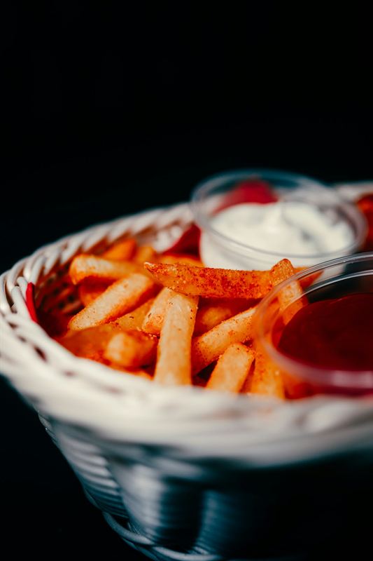 Gewürzte Pommes im Körbchen mit Dips
